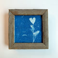 Framed artwork with blue topographic design and white heart shape on a light background