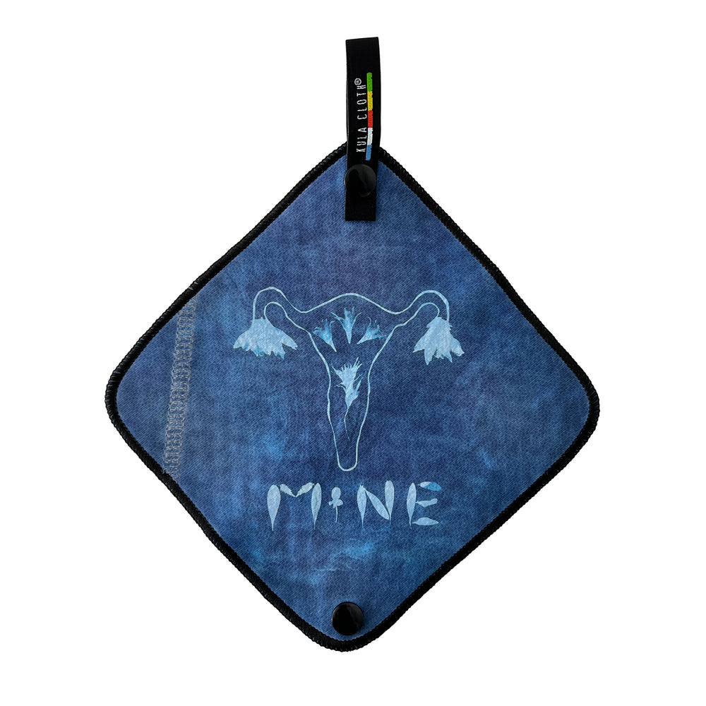 Blue towel with a uterus symbol and 'MINE' text on a white background